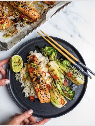 Glazed salmon with sesame seeds and sliced chilli on rice, with charred pak choi and chopsticks