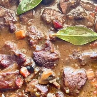 Mandy's boeuf bourguignon in the pan: dark, glossy beef and mushrooms with two bay leaves on top